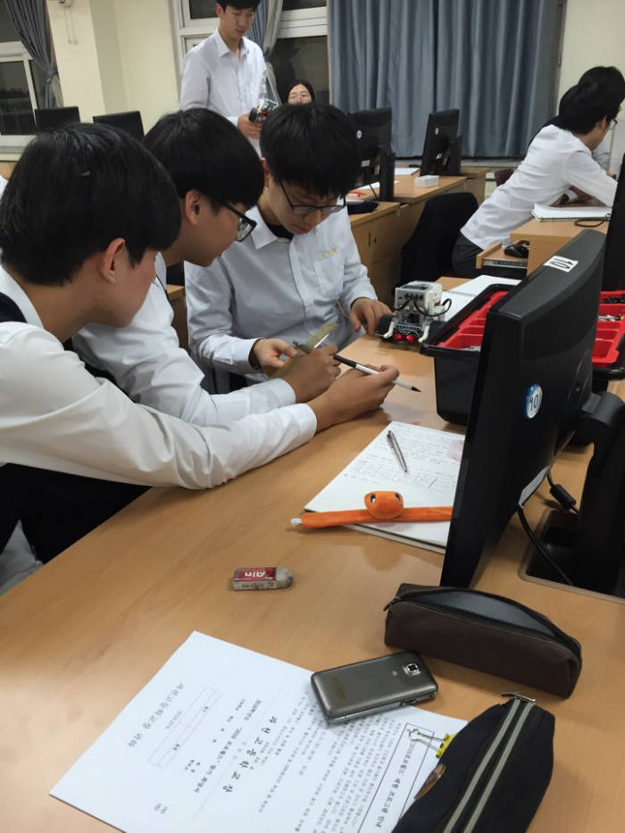 경기도 과천고 학생들이 소프트웨어 야간수업 시간에 모여 로봇 장애물 통과방법을 찾기 위해 토론중이다.