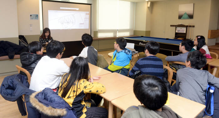 학생들이 웹툰 작가가 어떻게 그림을 그리는지 감상하고 있다.
